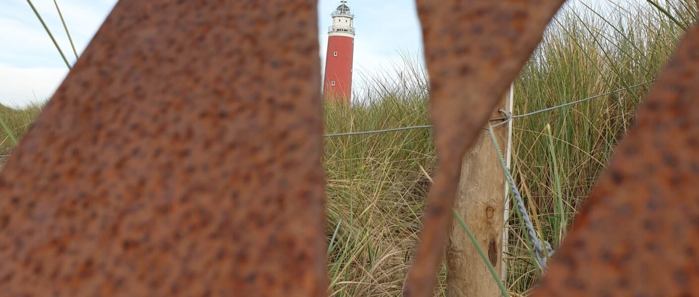 Door een "V" in metaal heen heb je uitzicht op de vuurtoren van Texel