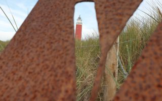 Door een "V" in metaal heen heb je uitzicht op de vuurtoren van Texel