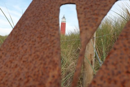 Door een "V" in metaal heen heb je uitzicht op de vuurtoren van Texel